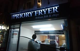 Priory fish and chips lit up at night.