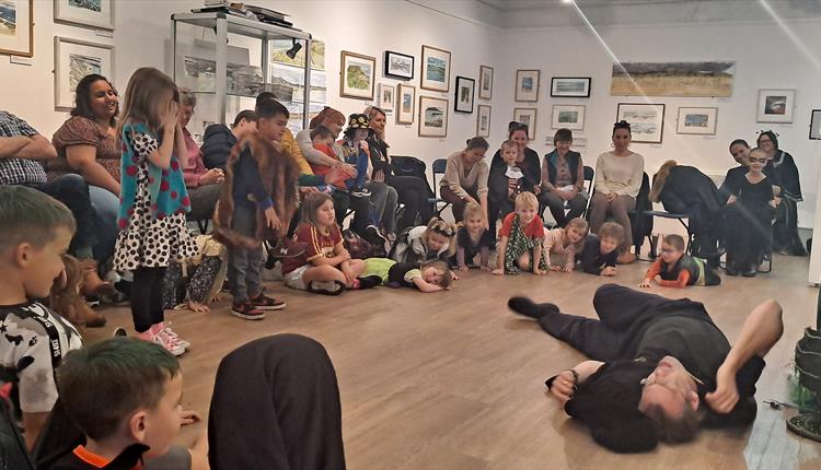 Children in costume watch an actor in the main gallery