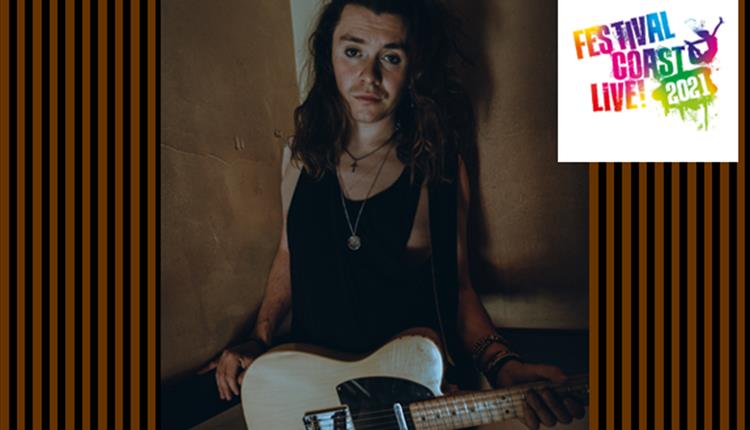 Alex with his guitar in darkened room