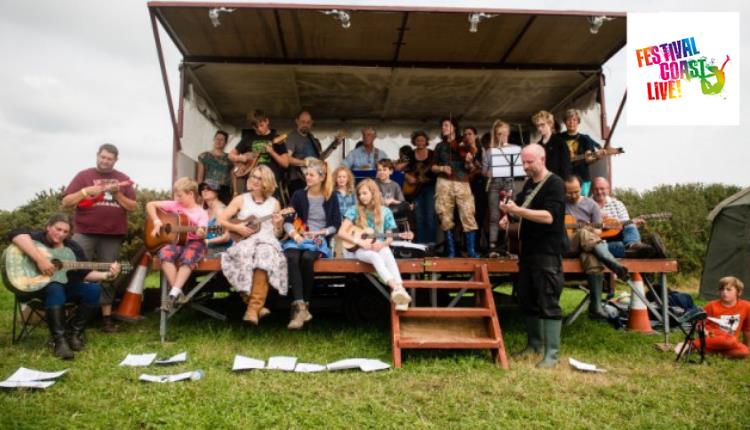 Various musicians sitting outside on a small stage some playing guitars