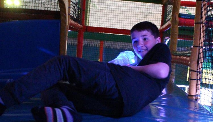 Boy climbing through a colourful soft play area