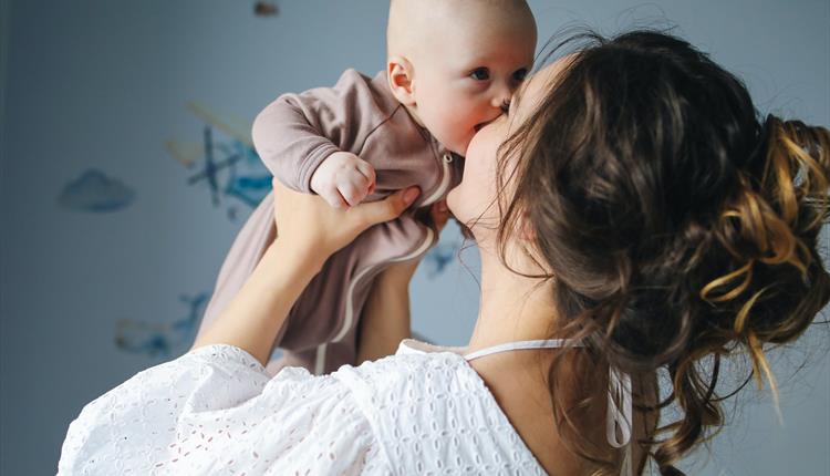 A woman hoisting a baby lovingly in her arms.