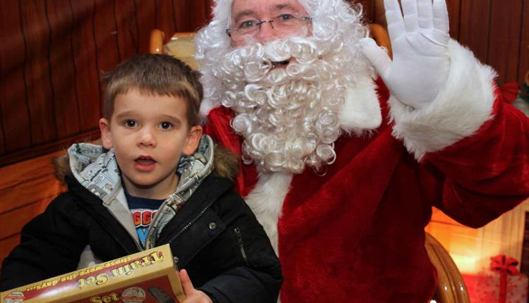 Boy sat on santas lap with a toy