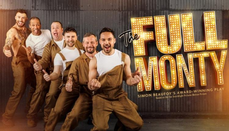 Six Performers in brown overalls and white t-shirts standing against a gray industrial background.