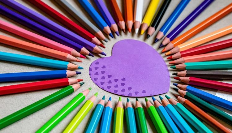 Purple paper heart surrounded by multicoloured pencils