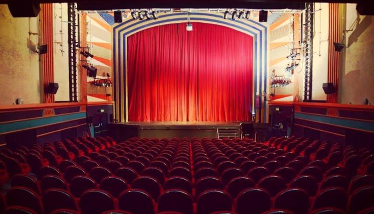 Red curtains on a stage with seats