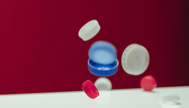 Many multicoloured bottle tops falling onto a white table