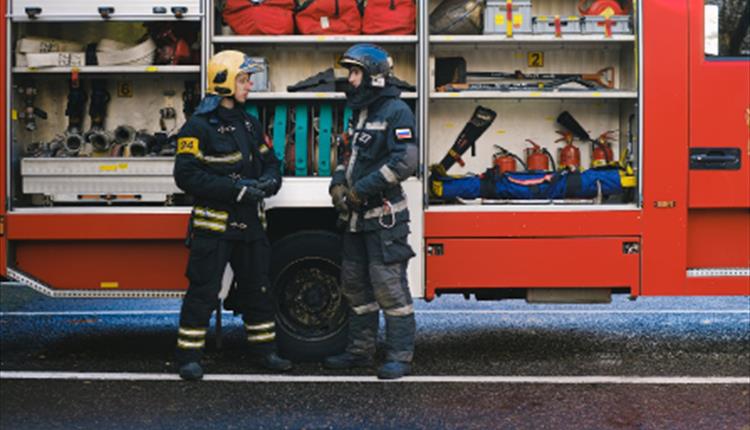 Two fireman talk outside their truck