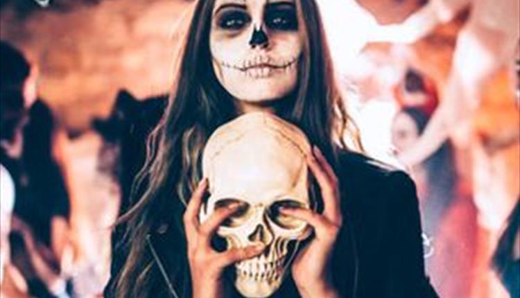 Woman dressed up as a skeleton, holding a skeleton