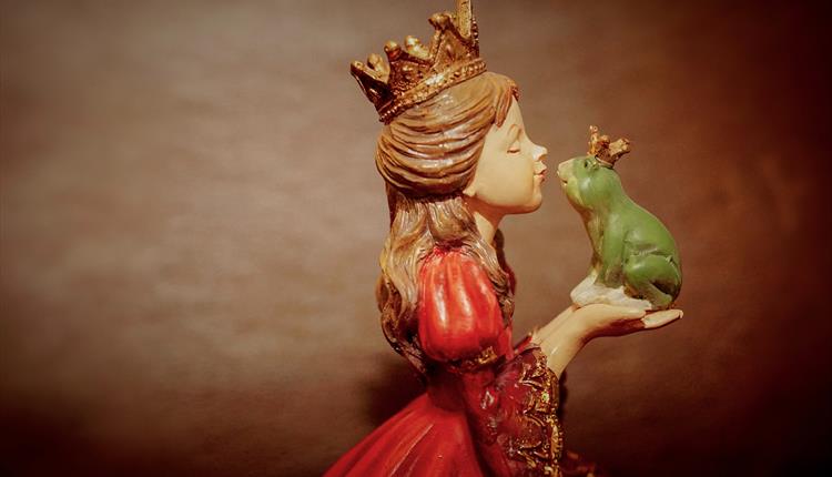 A princess preparing to kiss a frog held in her hands